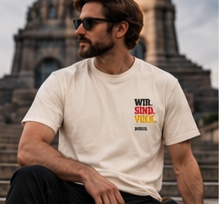 Lookbook-Konzept: naturhelles Shirt mit kleinem dreifarbigem Brustdruck, getragen im Sitzen.