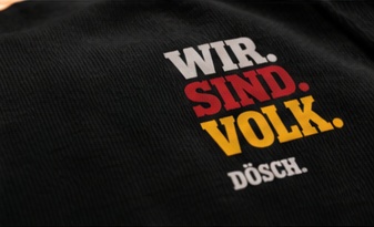 Vergrößerter Brustdruck aus der Lookbook-Vorlage: WIR. in hellem Ton, SIND. in Rot und VOLK. in Gold.